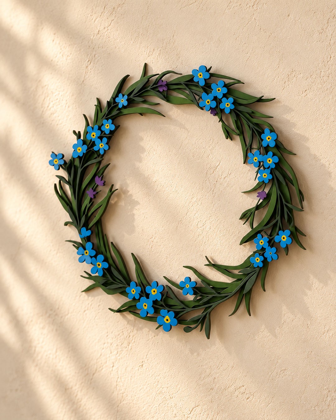 A wooden wreath of blue flowers and green leaves on a warm plaster wall