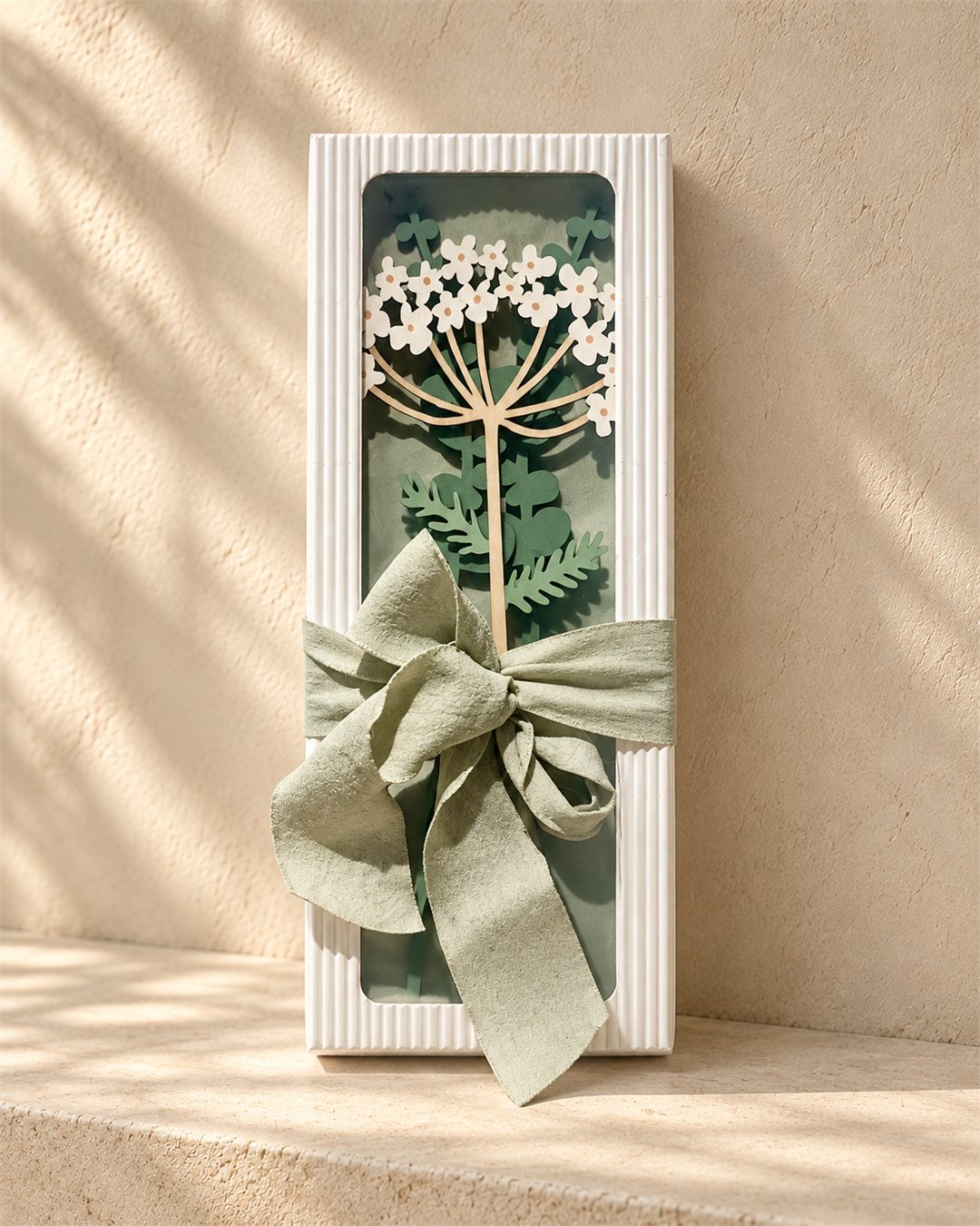 White floral wooden stem presented in a pale fluted gift box with a sage ribbon